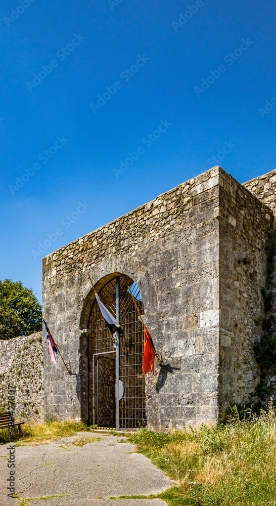 The medieval castle of the ancient village of Narni. Umbria, Terni, Italy. The stone walls and towers of the fortress. The entrance gate. The blue sky in summer.
