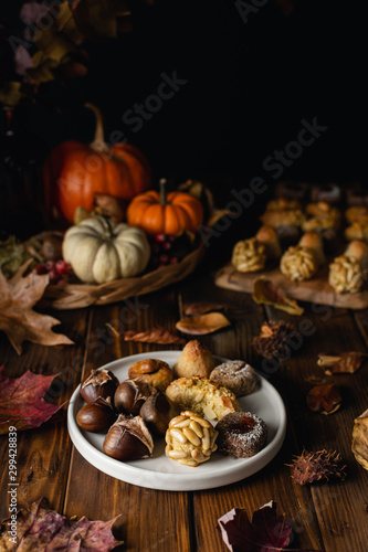 All Saints Day marzipan sweet panellets and roasted chestnuts, autumn leaves on wooden table photo