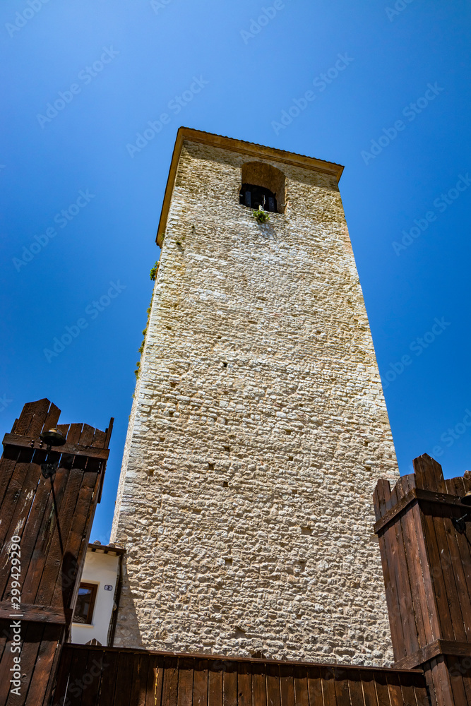 A medieval tower in the ancient village of Narni, with old stone and brick buildings. Umbria, Terni, Italy. The blue sky on a summer day.