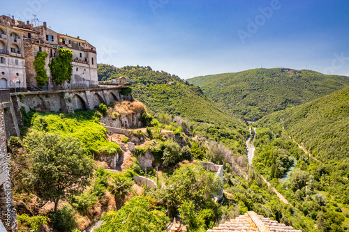 A characteristic glimpse of the ancient medieval village of Narni. Umbria, Terni, Italy. The blue sky on a summer day. The valley below with the green hills and the Nera river. Green trees.
