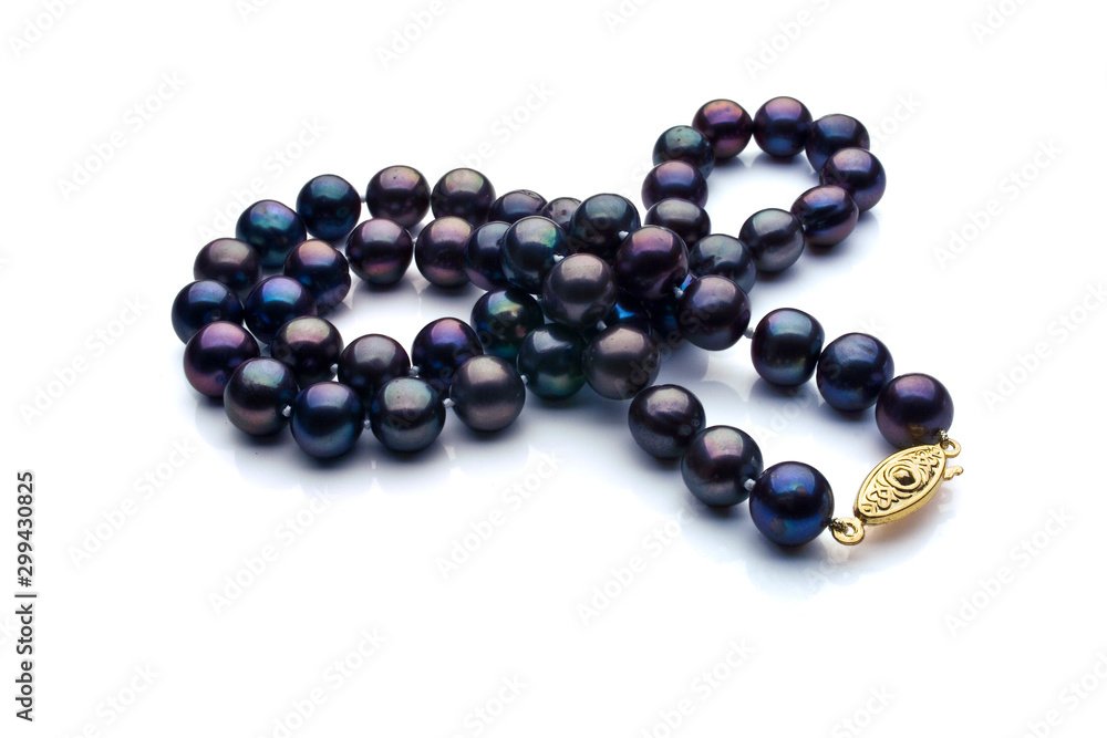 A necklace of black pearls with a gold clasp on a white background. A necklace of black pearls with a gold clasp on a white background.