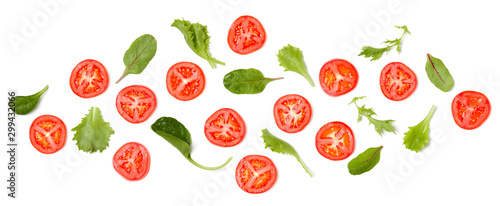 Creative layout made of tomato slices and salad leaves. Flat lay, top view. Vegetables isolated on white background. Food ingredient pattern.