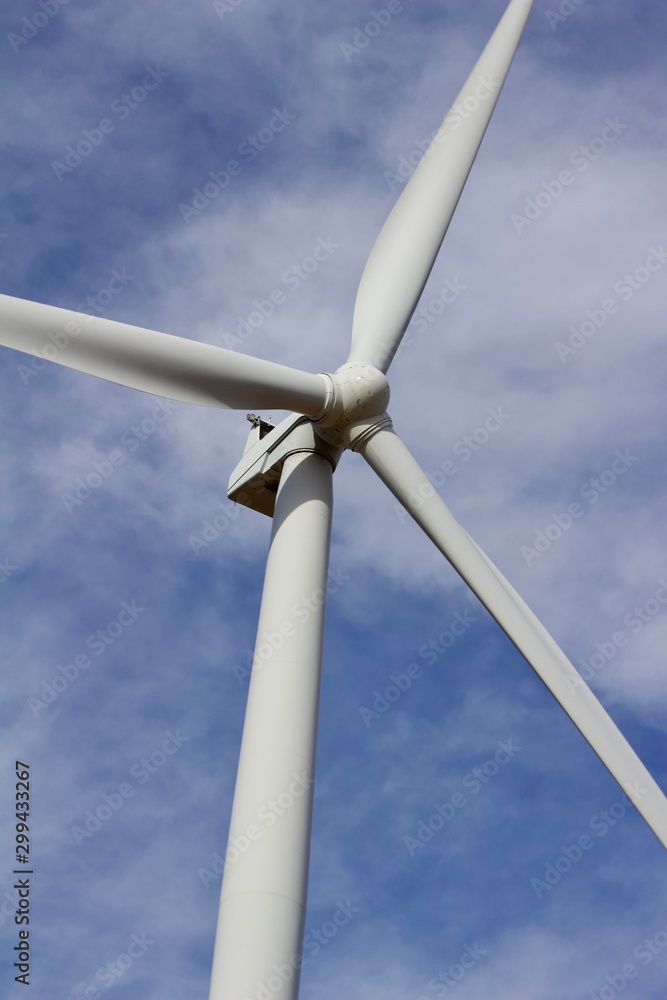 Close upward view of a giant wind power turbine propeller with a blue sky background Close upward view of a giant wind power turbine propeller with a blue sky background