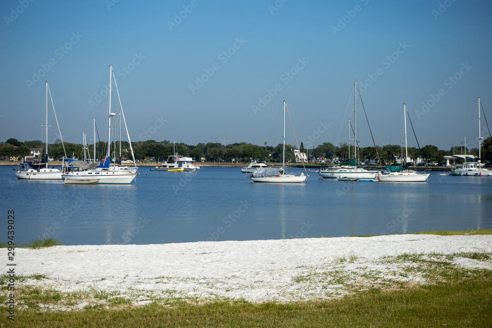 Sailboats moored in a calm bay off a white sandy shore. Sailboats moored in a calm bay off a white sandy shore.