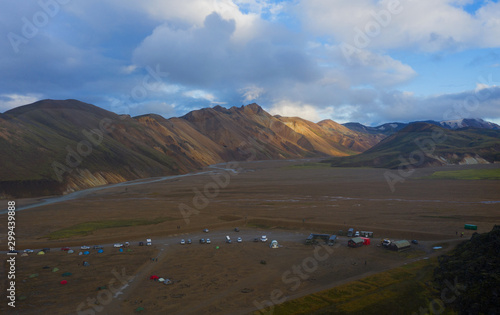 Iceland in september 2019. Great Valley Park Landmannalaugar, surrounded by mountains of rhyolite and unmelted snow. In the valley built large camp. The concept of world tours. Aerial drone shot.