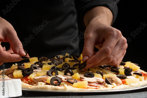 Chef cooks pizza, puts olives on the background with ingredients. Recipe book, menu, home cooking, pizzeria. Macro, close-up