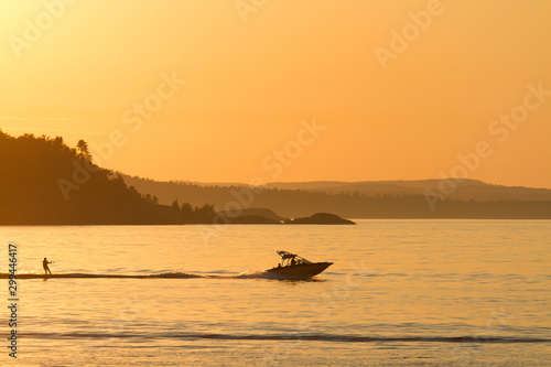 Silhouette of a boat and water skiier at sunset