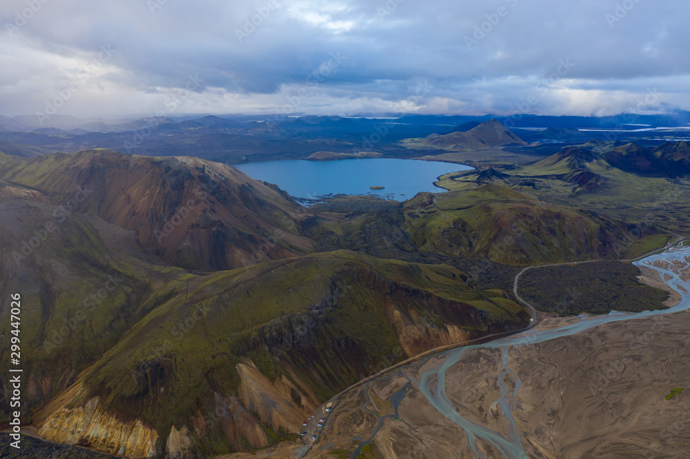 Iceland in september 2019. Great Valley Park Landmannalaugar, surrounded by mountains of rhyolite and unmelted snow. In the valley built large camp. The concept of world tours. Aerial drone shot.