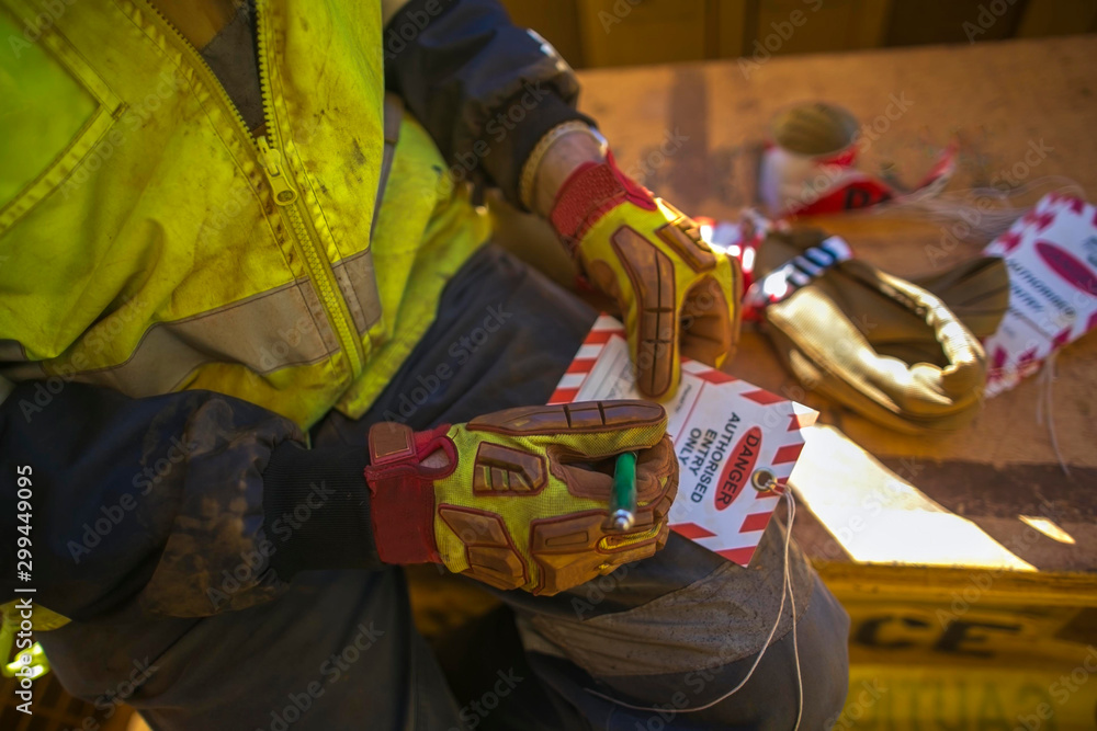 Male industrial construction worker rigger writhing details information on red and white danger