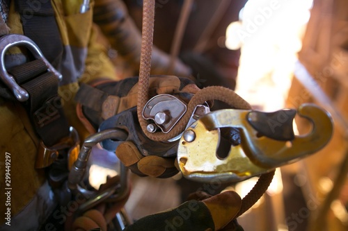 Picture of rope access technician hand opening descender and clipping connecting inserting with 10 MM low stretch Nylon abseiling rope attached into safety harness loop in locking positioning  photo