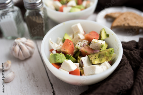 healthy salad from fresh vegetables with avocado, tomatoes and fresh mozzarella cheese served in white bowl