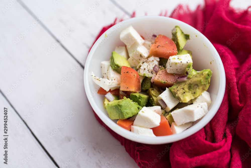 healthy salad from fresh vegetables with avocado, tomatoes and fresh mozzarella cheese served in white bowl healthy salad from fresh vegetables with avocado, tomatoes and fresh mozzarella cheese served in white bowl