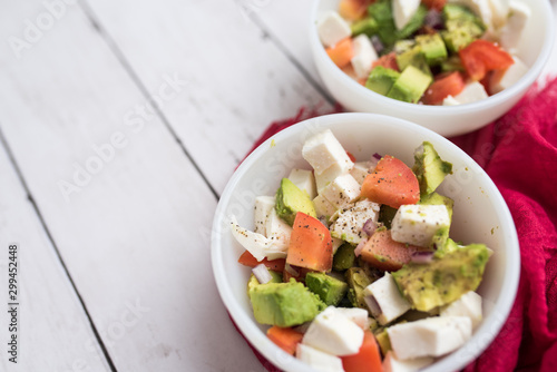 healthy salad from fresh vegetables with avocado, tomatoes and fresh mozzarella cheese served in white bowl