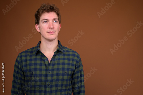 Face of young handsome hipster man in green checkered shirt