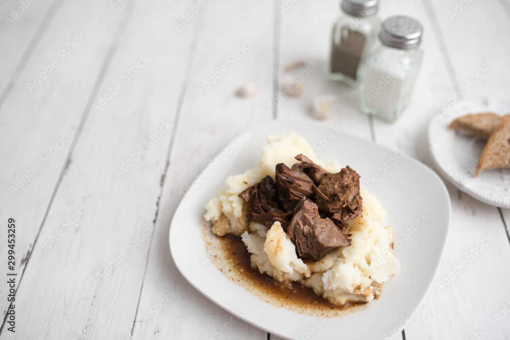 Beef tips with gravy on mashed potatoes served on white plate Beef tips with gravy on mashed potatoes served on white plate