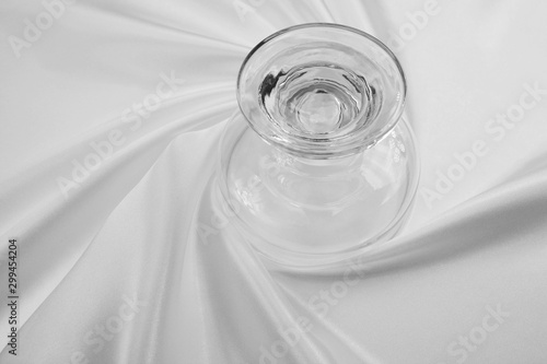 Delicate satin draped fabric white and glass wine glass for festive backgrounds