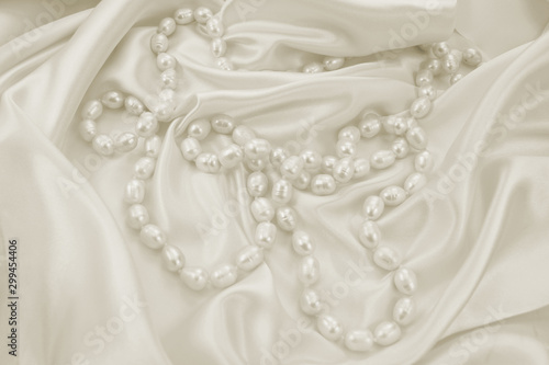 Delicate white satin draped fabric with natural river pearls for festive backgrounds
