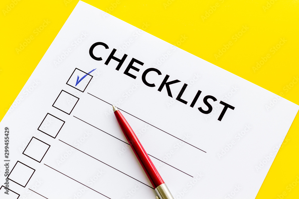 Checklist close up and pen on yellow background top view Checklist close up and pen on yellow background top view