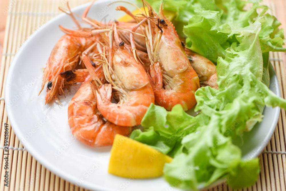 prawns shrimps cooked burnt barbecue with lemon and vegetable salad - shrimp grilled bbq seafood on white plate table food prawns shrimps cooked burnt barbecue with lemon and vegetable salad - shrimp grilled bbq seafood on white plate table food