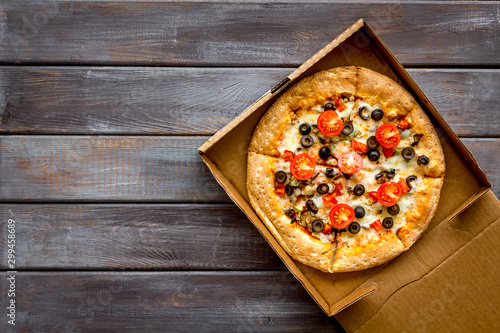 Pizza delivery. Italian food in box on dark wooden background top view copy space