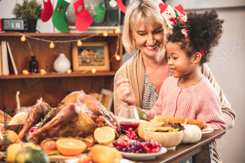 Little Girl Eating and smile Thanksgiving Celebration Concept. grandmother and granddaughter eating and smile at freshly prepared turkey for thanksgiving dinner.