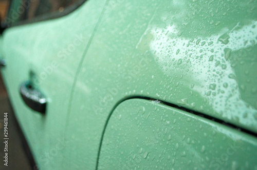 Beautiful rain drops on the car of trendy tranquil dawn or neo mint color. Wet car body of trendy tranquil dawn color.