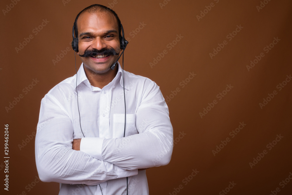 Portrait of happy Indian businessman with mustache as call center representative Portrait of happy Indian businessman with mustache as call center representative