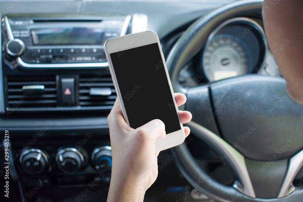 Closeup image of a hand using a smartphone on a car while driving, searching for directions. Travel Concept