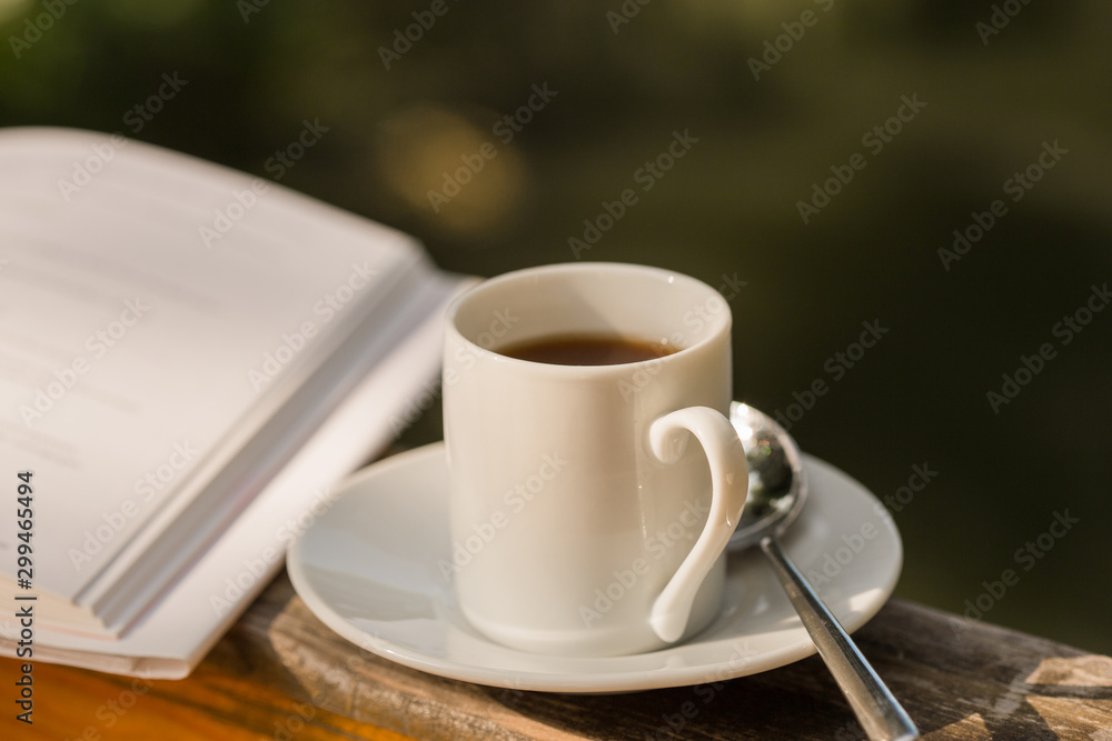 cup of coffee and open book on wooden natural outdoor table cup of coffee and open book on wooden natural outdoor table