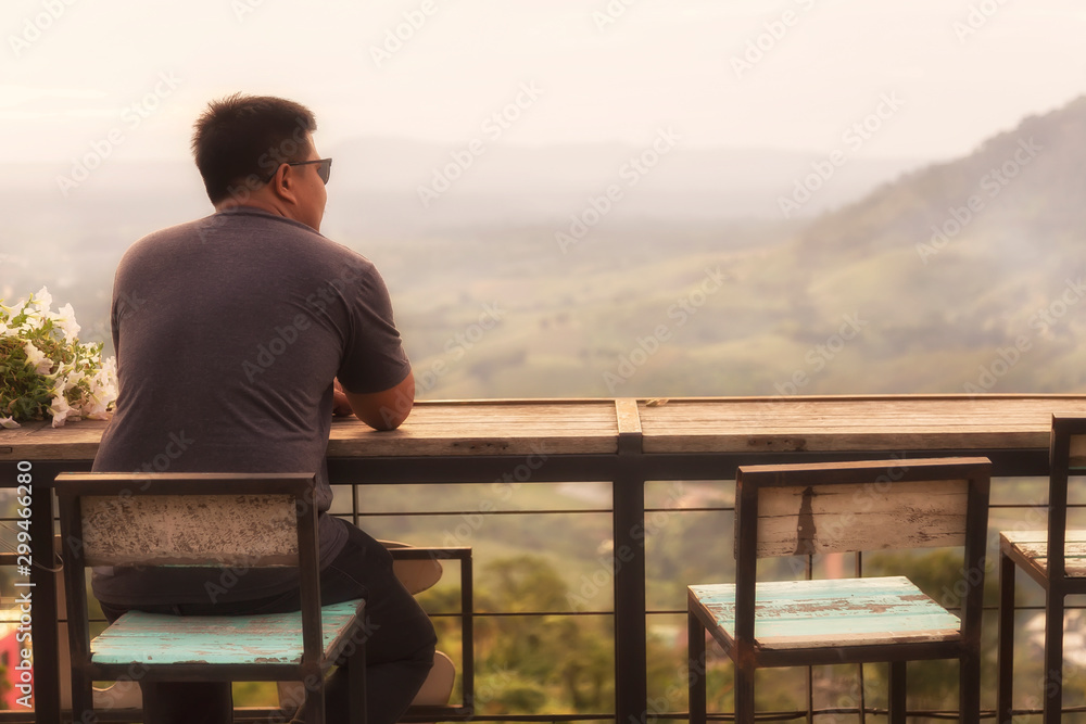 Asian man is standing on the balcony to see the beautiful sunset at Petchabun provice , Thailand.