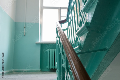 Staircase at the entrance of an apartment building. View from below. You can see the railing, grille, window. New repairs in the entrance.