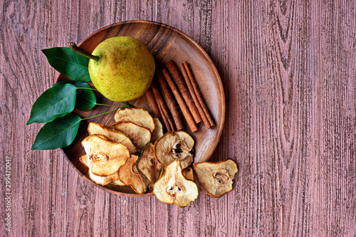 Cinnamon pear chips with fresh pears Dried fruits. Healthy sweet snack. Vegetarian Vegetarian appetizer on a wooden plate.