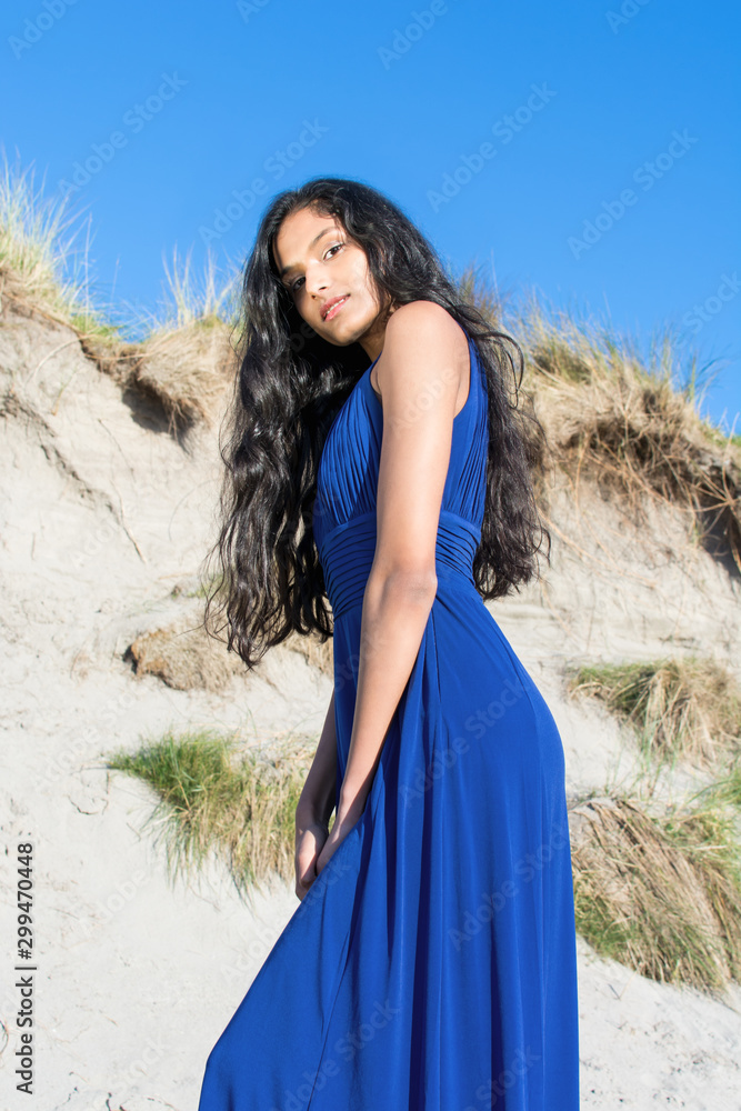 Beautiful model looking down at camera at the beach in Sligo in Ireland.  Mixed race Portuguese Indian female model posing. Blue dress. Black hair  model. Irish coastline. Photos | Adobe Stock