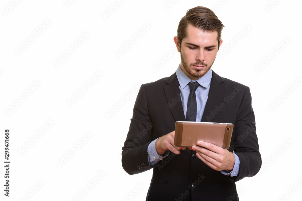 Portrait of young handsome bearded businessman in suit using digital tablet Portrait of young handsome bearded businessman in suit using digital tablet