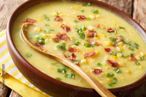 Thick homemade corn chowder with potatoes, bacon and green onions close-up in a bowl. horizontal