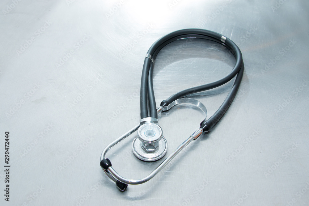 Medical phonendoscope (stethoscope) on a metal table. A diagnostic