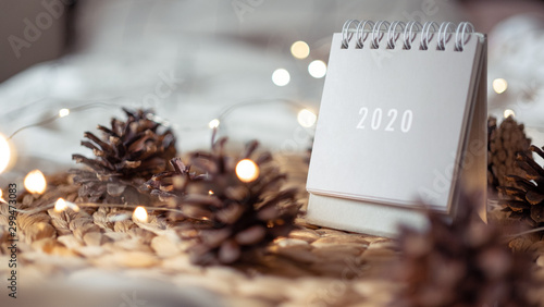 New Year 2020 calendar with lights on rustic server with cones and toys