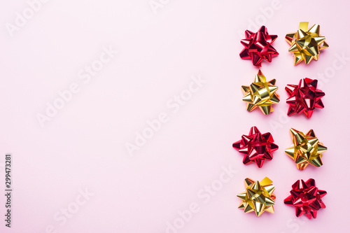 Gold and red Christmas bows on pink background. Gift concept greetings for holidays birthday Wedding New year Christmas mother s Day. Copy space.