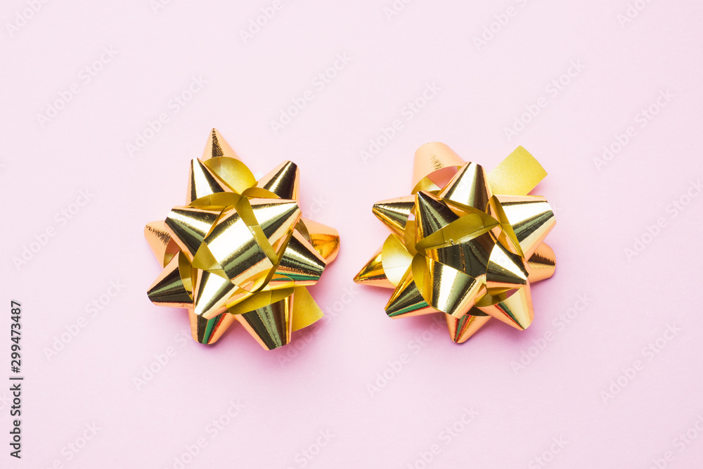 Gold Christmas bows on pink background. Gift concept greetings for holidays birthday Wedding New year Christmas mother's Day. Copy space. Gold Christmas bows on pink background. Gift concept greetings for holidays birthday Wedding New year Christmas mother's Day. Copy space.
