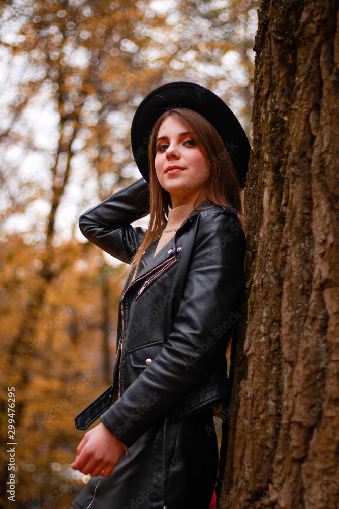 Stylish autumn girl in the park. Sweater, hat and leather jacket and leather skirt. Atmosphere. Makeup Stylish autumn girl in the park. Sweater, hat and leather jacket and leather skirt. Atmosphere. Makeup