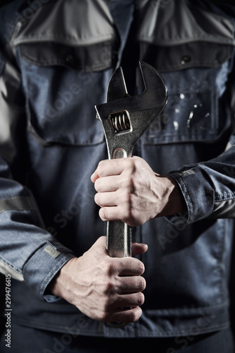 Professional construction worker shows a wrench on a dark background