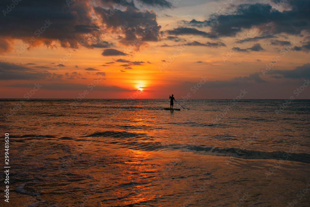 Silhouette of the man  n padding board in sunset in the sea 