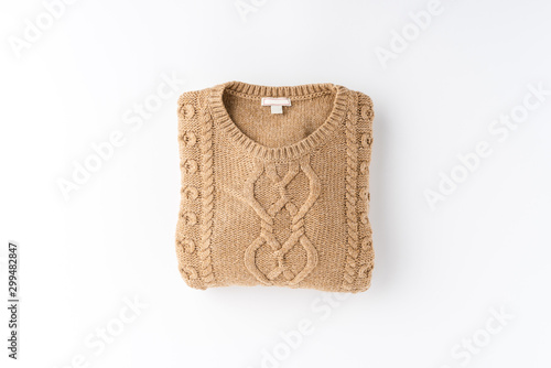 Beige folded sweater isolated on white background. Flat lay. Top view