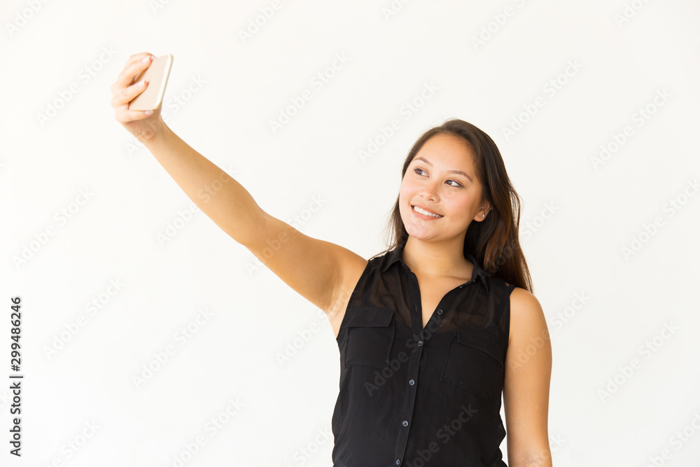 Content woman taking selfie with cell phone. Beautiful happy young woman taking selfie with smartphone on white background. Selfie concept Content woman taking selfie with cell phone. Beautiful happy young woman taking selfie with smartphone on white background. Selfie concept