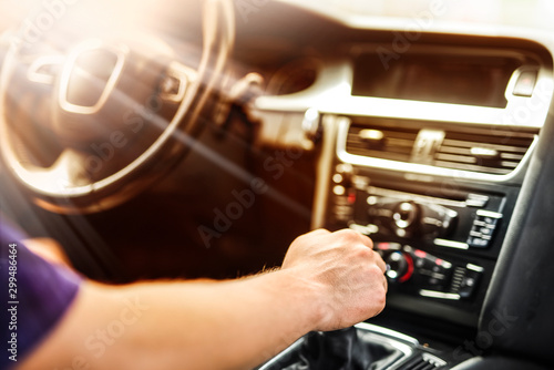Man using gear on car manual gearbox for driving close up. Vehicle dashboard in background blured. Shifting the gear stick detail.