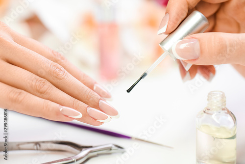Beautician in luxury salon applying lacquer or varnish gel on nails..Manicure nail paint with brush or artist polish modelation technique.