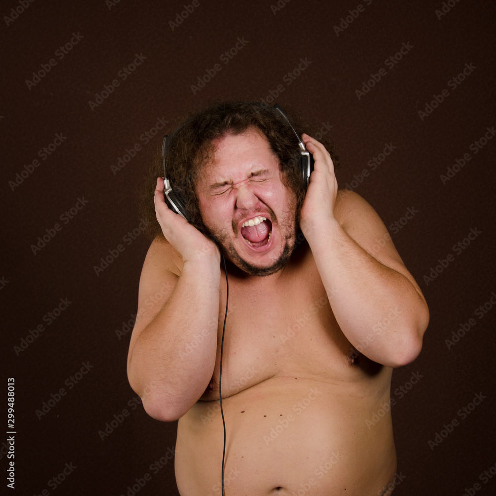 Funny fat guy listens to music on headphones. Stock Photo | Adobe Stock