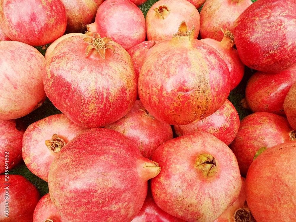 Bright red pomegranates close-up. Ripe juicy pomegranates on counter of bazaar or greengrocer. Selective focus image. Bright red pomegranates close-up. Ripe juicy pomegranates on counter of bazaar or greengrocer. Selective focus image.