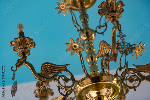 Gold candlestick chandelier with azure ceiling in the background.