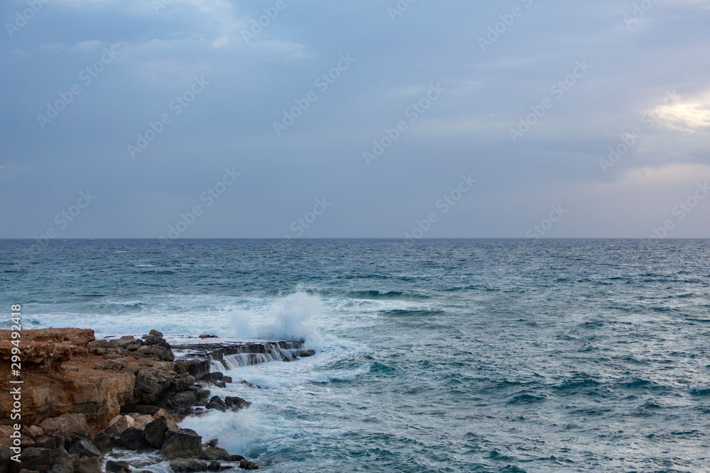 Wave breaking against cliff, Agia Napa, Cyprus.. White spray in the air. Clear turquoise water in foreground.